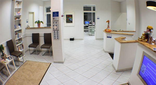 Heller Wartebereich einer modernen Arztpraxis mit Empfangstresen und Sitzgelegenheiten.