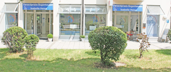 Fassade der Tierarztpraxis Bogenhausen mit grüner Vorgartenfläche und Schaufenstern.