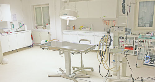 Moderner Operationssaal mit OP-Tisch, medizinischen Geräten und heller Beleuchtung.